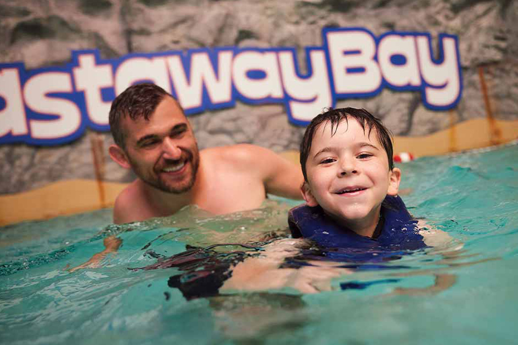 Adult and child enjoying Castaway Bay's indoor pool.